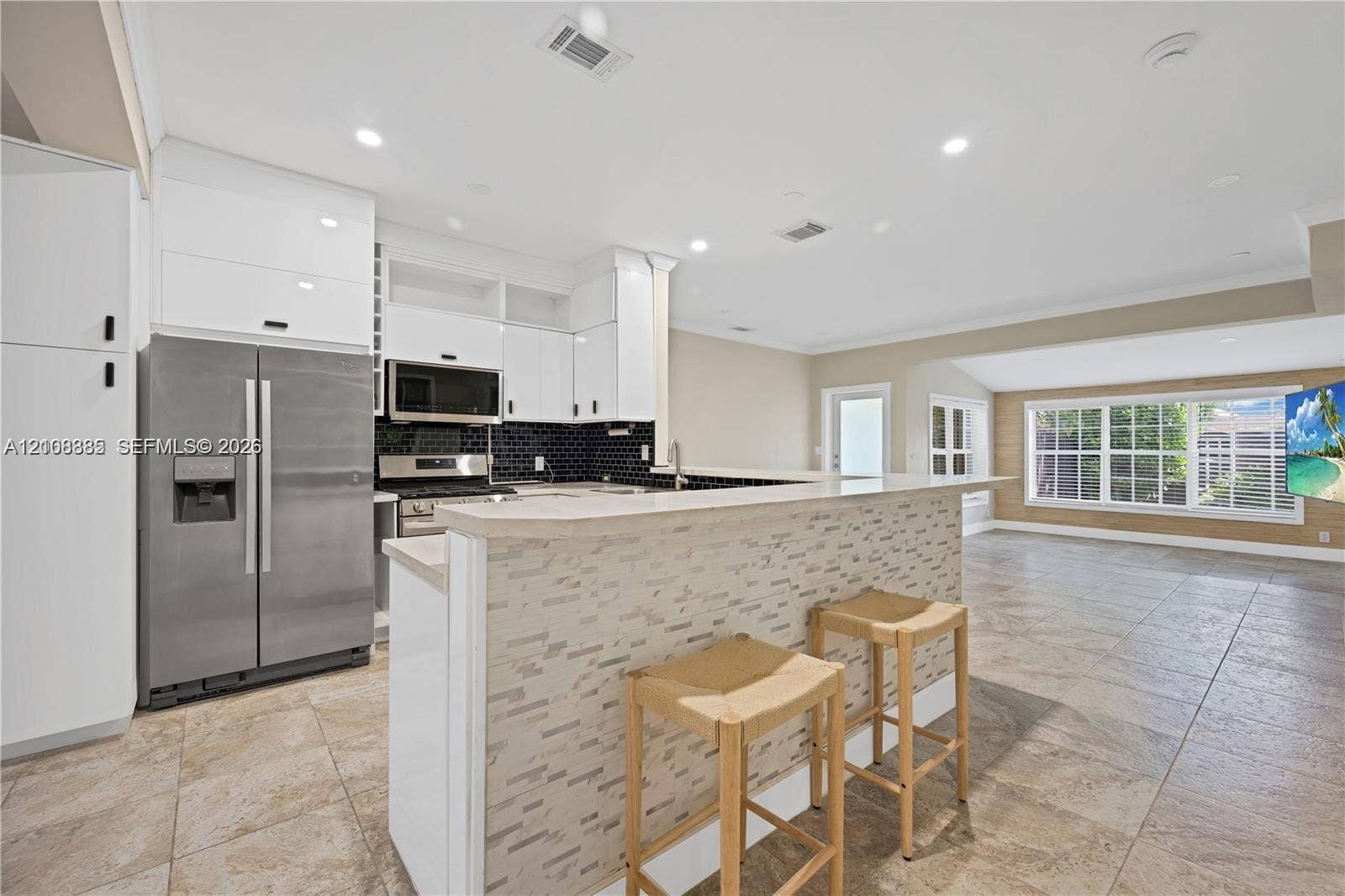818 NE 3rd Street, Hallandale Beach, Hallandale Beach, FL 33009 Kitchen featuring white flat-panel cabinetry, stainless steel appliances, a stone-tile breakfast bar, and tile flooring
