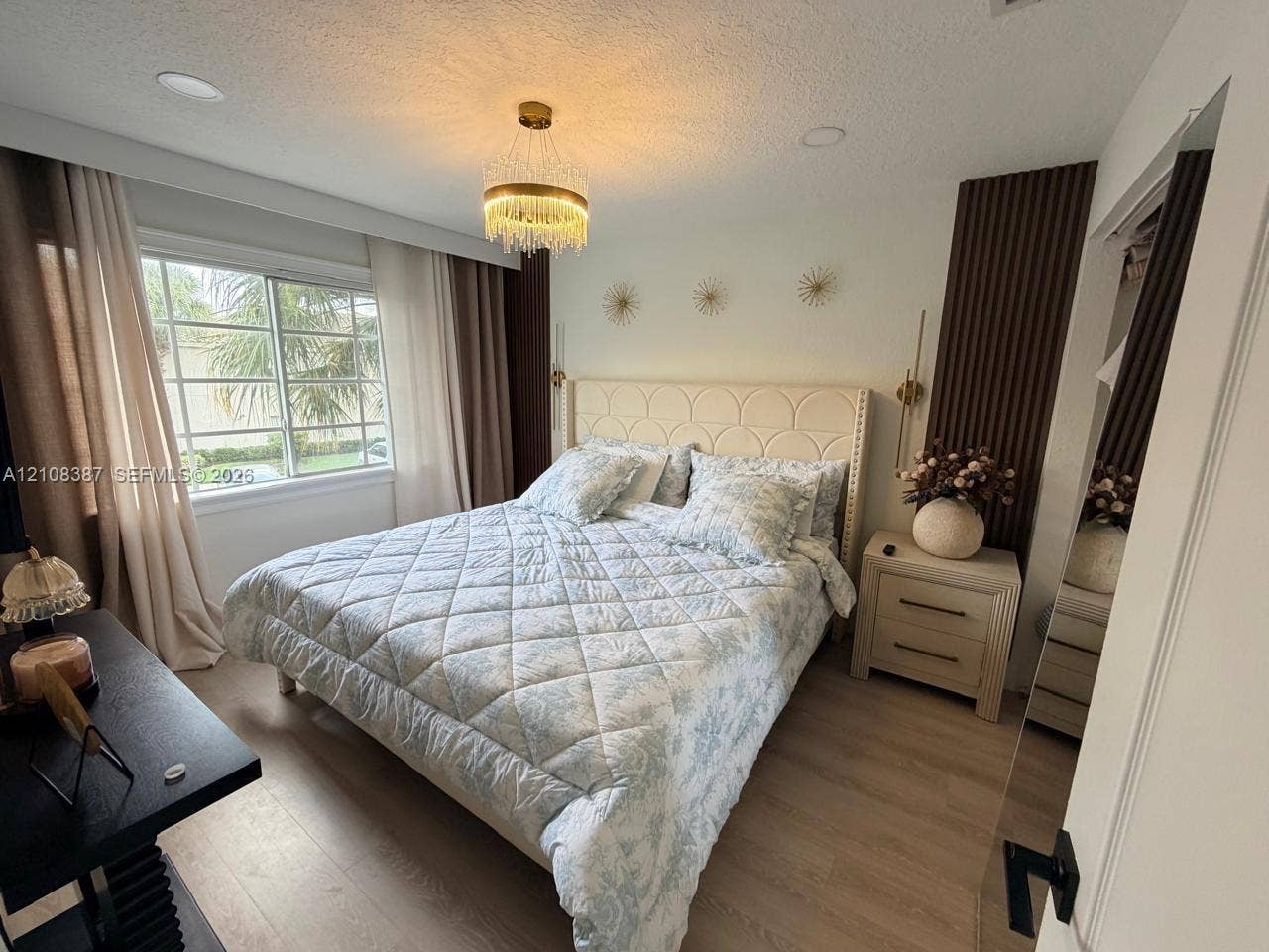 5703 NW 48th Avenue, Coconut Creek, FL 33073 Bedroom featuring recessed ceiling lighting, a circular tiered crystal chandelier, wood-finish flooring, and vertical wood-slat accent wall detailing