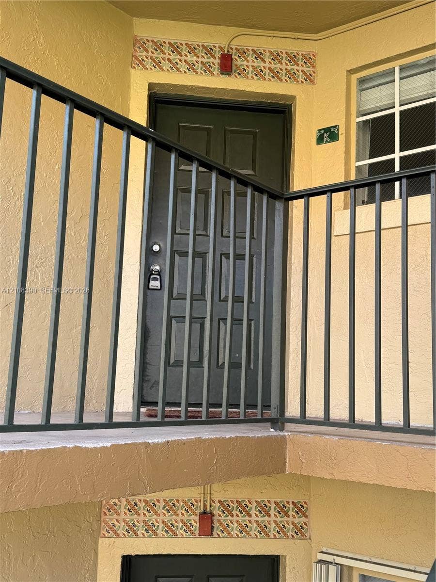 18346 NW 68th Avenue, #K, Hialeah, Hialeah, FL 33015 Exterior entry featuring a multi-panel door, metal balcony railing, and decorative tile accents