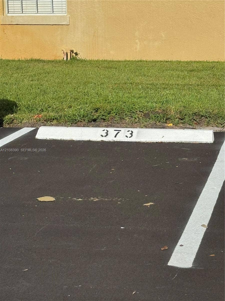 18346 NW 68th Avenue, #K, Hialeah, Hialeah, FL 33015 Assigned parking space featuring painted concrete wheel stop, asphalt surface, and painted stall demarcations