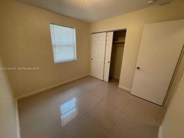18233 Oleta Drive, #18233, North Miami Beach, North Miami Beach, FL 33160 Neutral-toned ceramic tile flooring, sliding bifold closet doors, and a window with integrated blinds