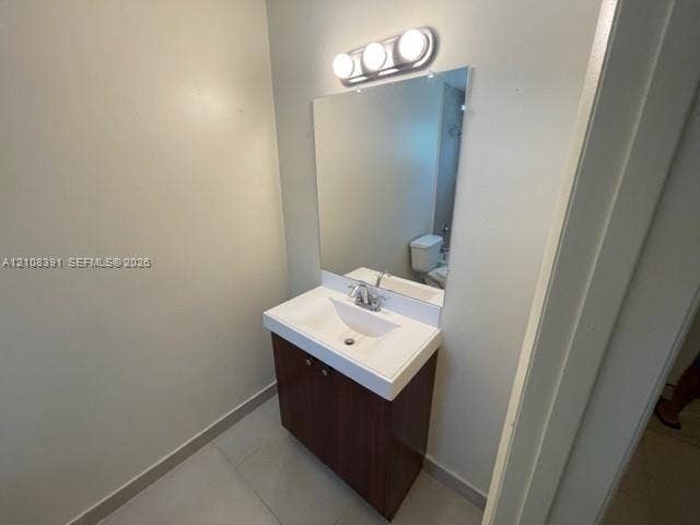18233 Oleta Drive, #18233, North Miami Beach, North Miami Beach, FL 33160 Vanity with integrated sink basin, dark wood-finish cabinetry, rectangular wall mirror, three-bulb vanity lighting fixture, and ceramic tile flooring