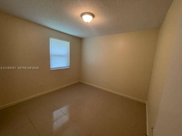 18233 Oleta Drive, #18233, North Miami Beach, North Miami Beach, FL 33160 Interior room featuring large-format tile flooring, neutral wall paint, and a single-window configuration with integrated blinds
