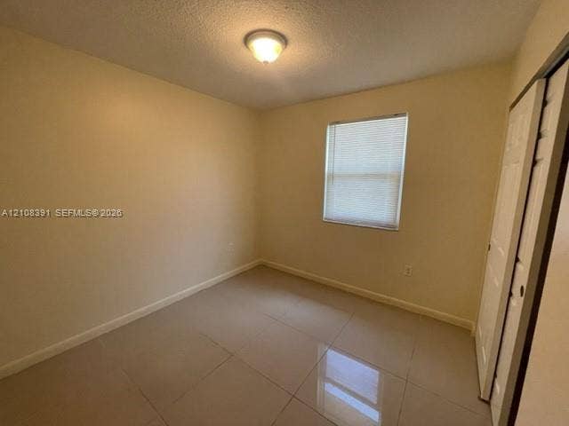 18233 Oleta Drive, #18233, North Miami Beach, North Miami Beach, FL 33160 Room featuring neutral wall paint, tile flooring, a window with horizontal blinds, a ceiling-mounted light fixture, and a built-in closet with sliding doors