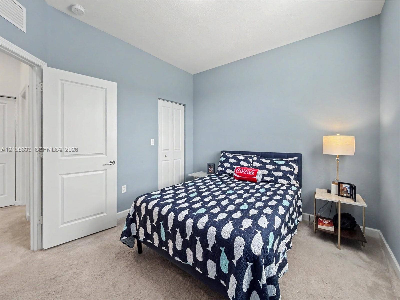Neutral-toned interior space featuring wall-to-wall carpeting, light blue painted walls, and white multi-panel interior doors
