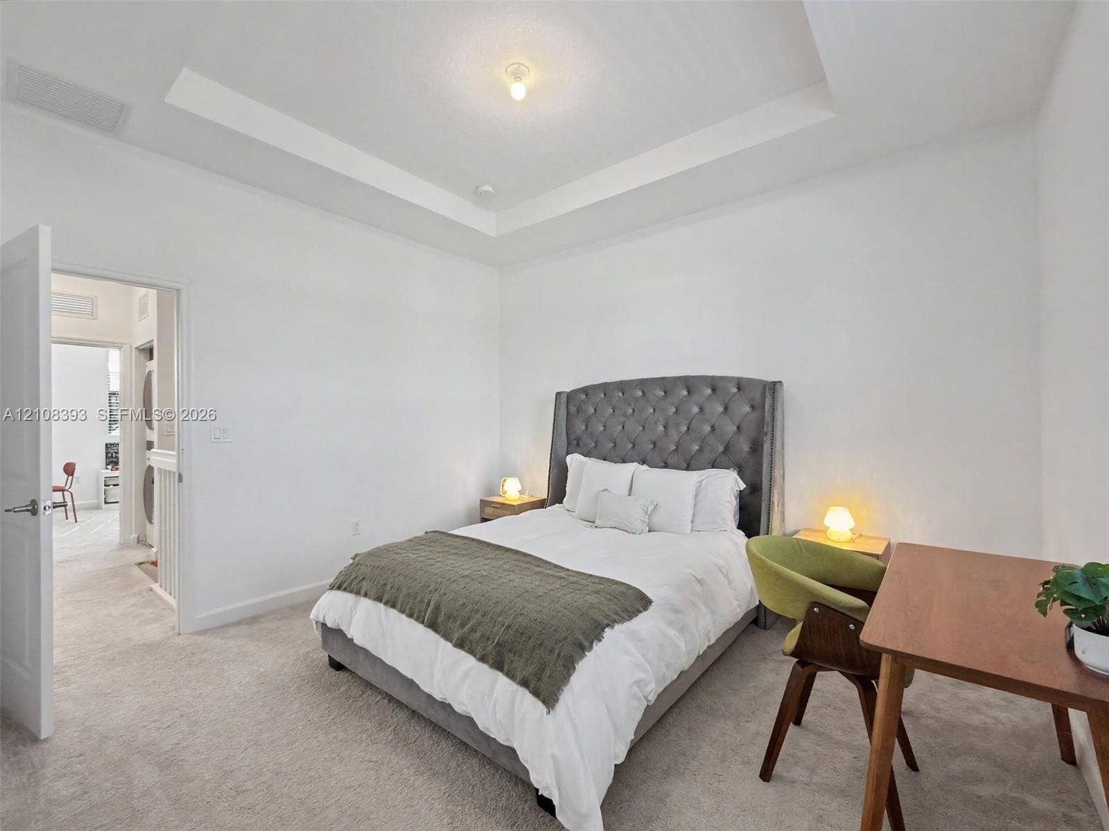Tray ceiling with center-mounted light fixture and neutral wall-to-wall carpeting