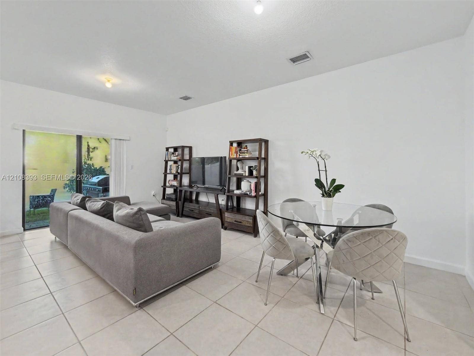 Neutral tile flooring, expansive sliding glass door, and recessed lighting