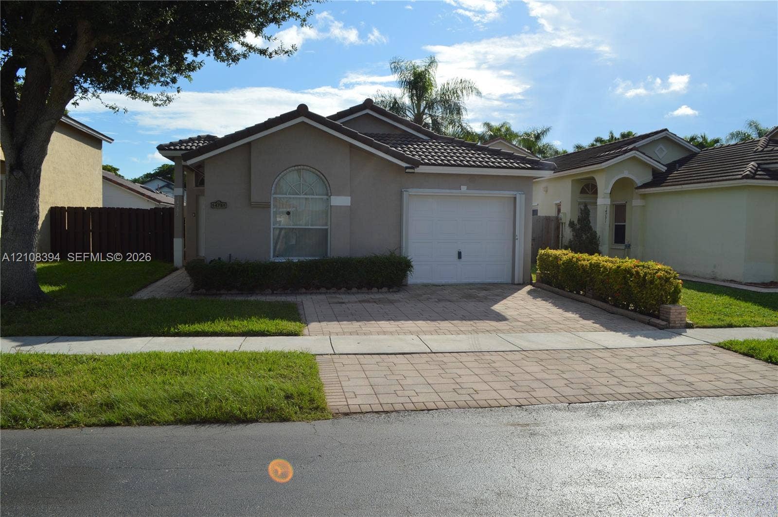 14781 SW 156th Avenue, Miami, Miami, FL 33196 Single-story residence featuring a tile roof, neutral stucco exterior, arched window detail, and an attached garage with a paved driveway
