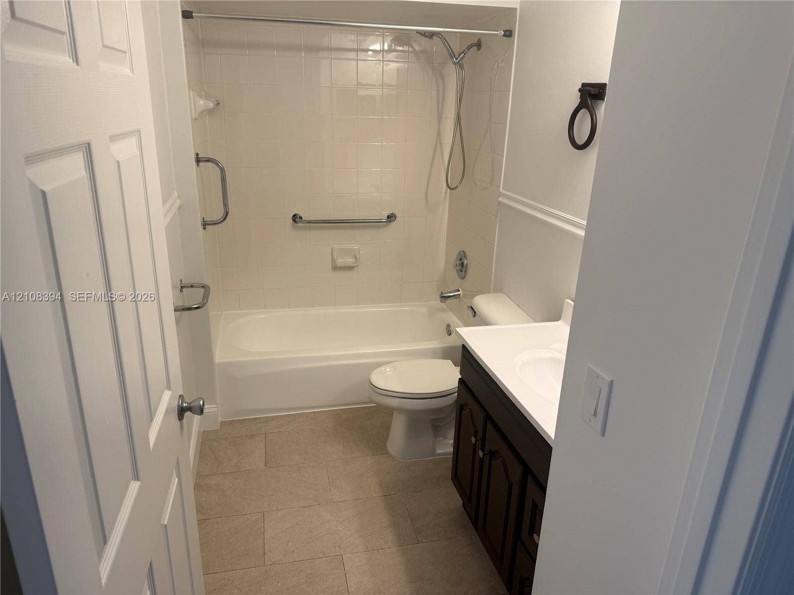 14781 SW 156th Avenue, Miami, Miami, FL 33196 Bathroom featuring a deep-basin tub with a tiled surround, a dark wood-finish vanity with a white countertop, and stone-tile flooring