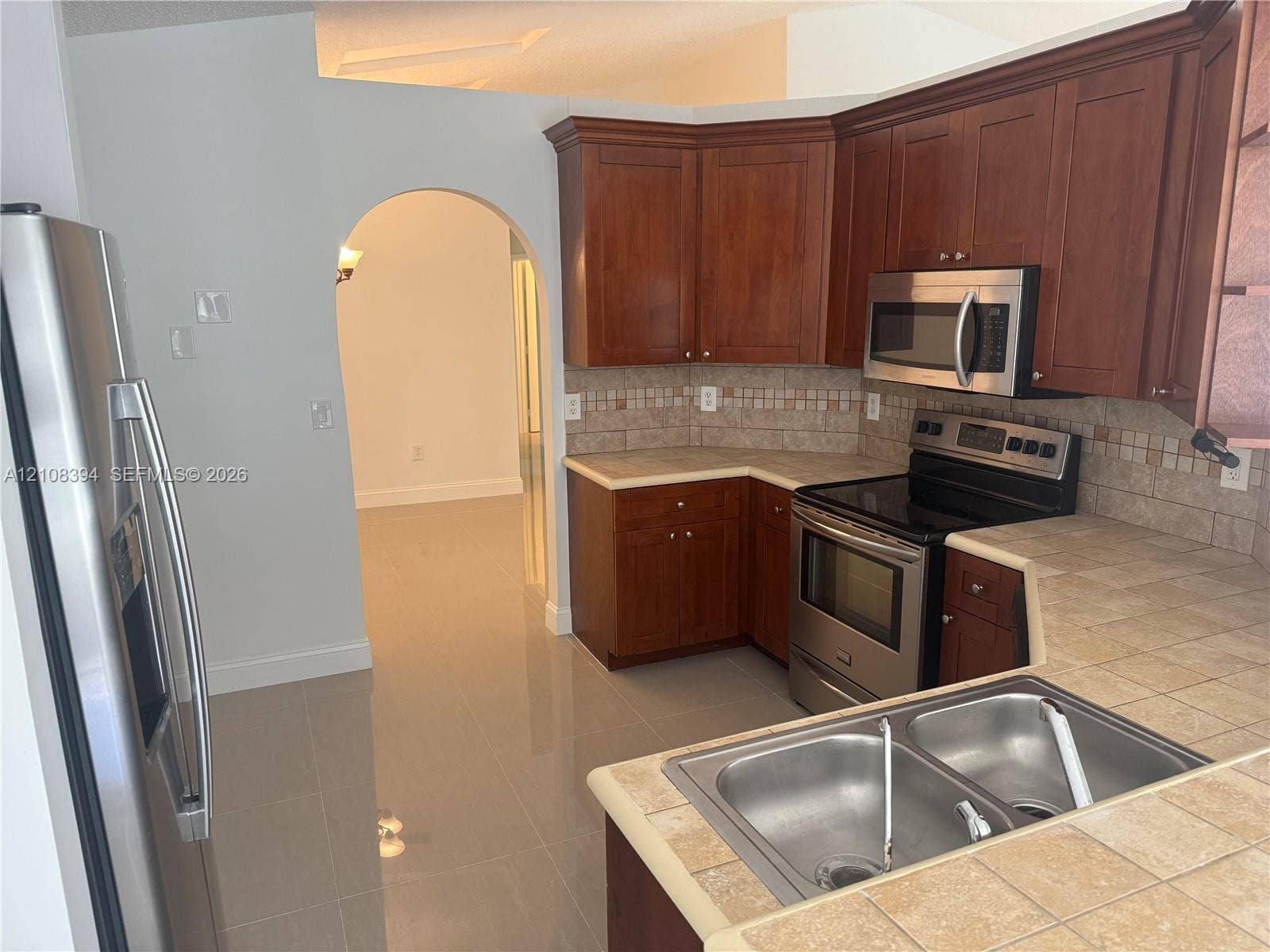 14781 SW 156th Avenue, Miami, Miami, FL 33196 Kitchen featuring cherry-finish cabinetry, stainless steel appliances, tile countertops, a mosaic tile backsplash, and ceramic tile flooring