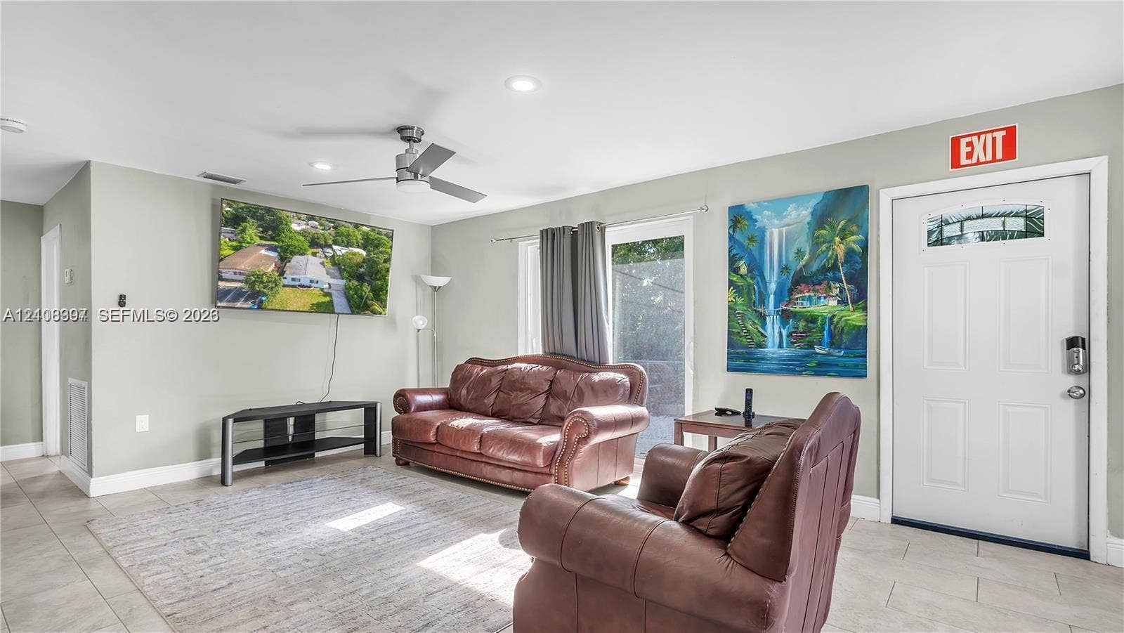 Neutral-tone interior featuring tile flooring, recessed lighting, a brushed-metal ceiling fan, and a glass-paned exterior door