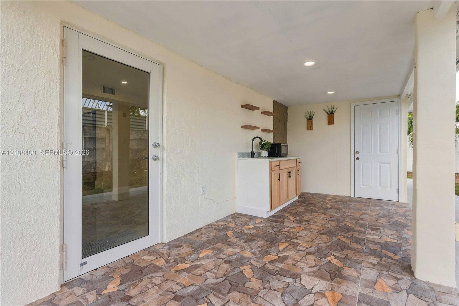 2551 SW 53rd Avenue, West Park, West Park, FL 33023 Covered patio featuring stone-tiled flooring, built-in cabinetry with a sink, recessed lighting, and a glass-panel door