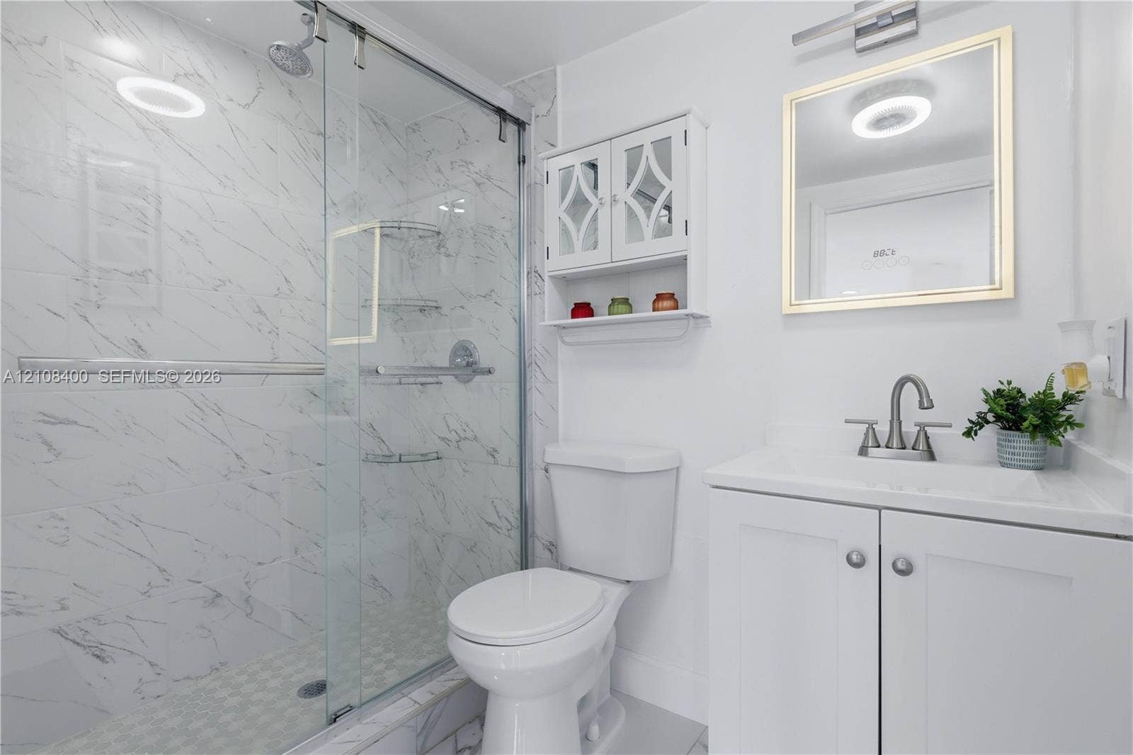 2551 SW 53rd Avenue, West Park, West Park, FL 33023 Bathroom featuring a glass-enclosed shower with floor-to-ceiling stone-pattern tile, white vanity cabinet with a integrated sink, polished metal hardware, and wall-mounted storage cabinetry