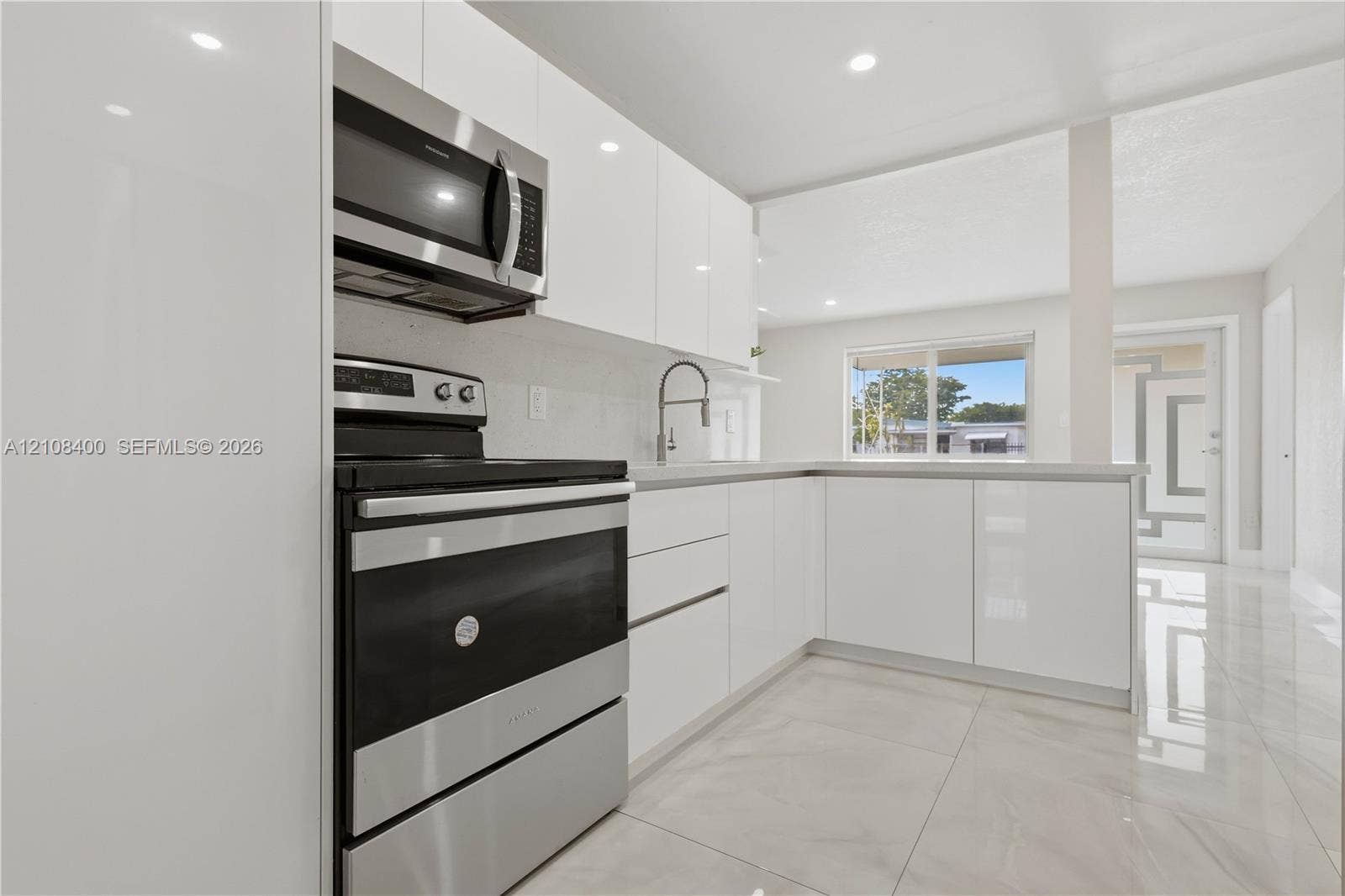 2551 SW 53rd Avenue, West Park, West Park, FL 33023 Kitchen featuring high-gloss white cabinetry, stainless steel appliances, neutral stone-finish flooring, and recessed lighting