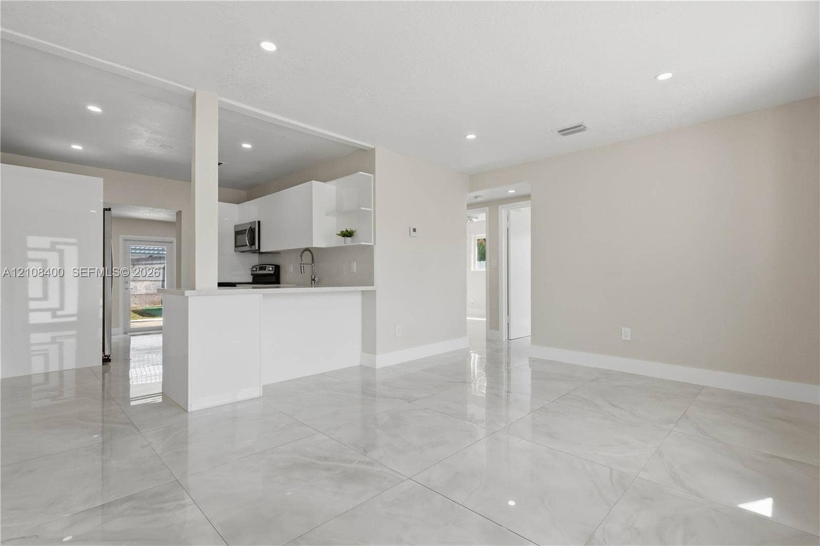 2551 SW 53rd Avenue, West Park, West Park, FL 33023 Open-concept interior featuring large-format tile flooring, white cabinetry, integrated peninsula, and recessed lighting