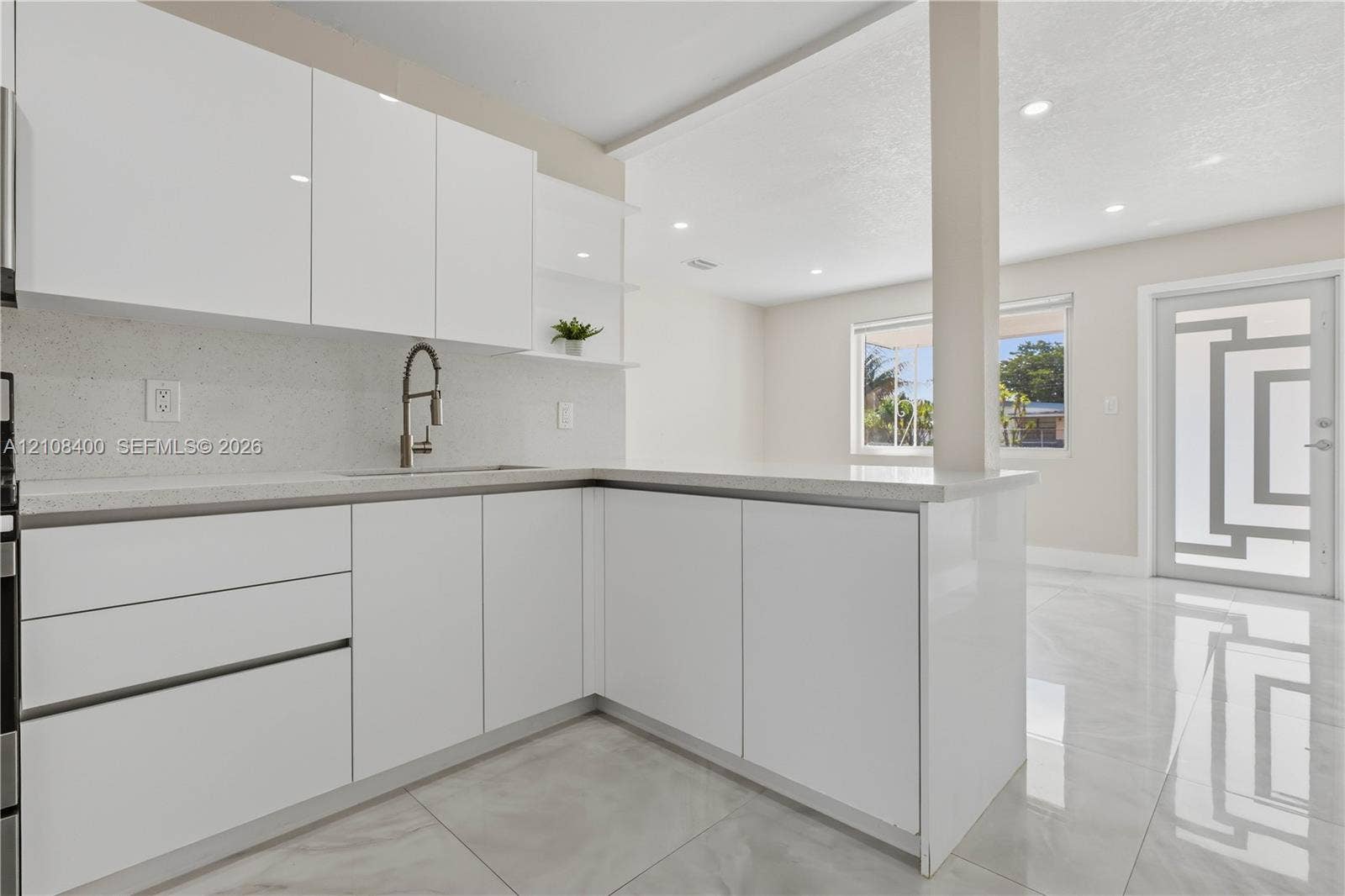 2551 SW 53rd Avenue, West Park, West Park, FL 33023 Kitchen featuring high-gloss white cabinetry, quartz countertops, a gooseneck faucet, large-format tile flooring, and a glass-paneled exterior door