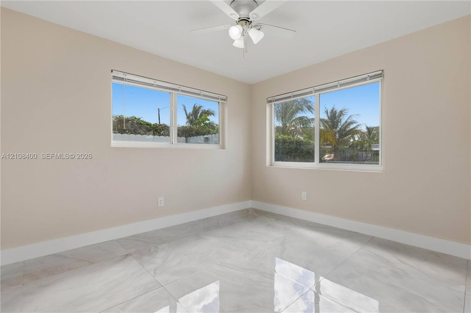 2551 SW 53rd Avenue, West Park, West Park, FL 33023 Room featuring large-format tile flooring, dual windows with integrated blinds, and a ceiling-mounted light fixture with a three-blade fan