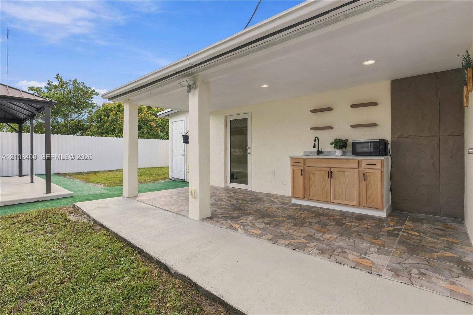2551 SW 53rd Avenue, West Park, West Park, FL 33023 Covered patio featuring stone-tile flooring, recessed lighting, and an outdoor kitchenette with light wood-finish cabinetry, a stone countertop, and a matte black faucet