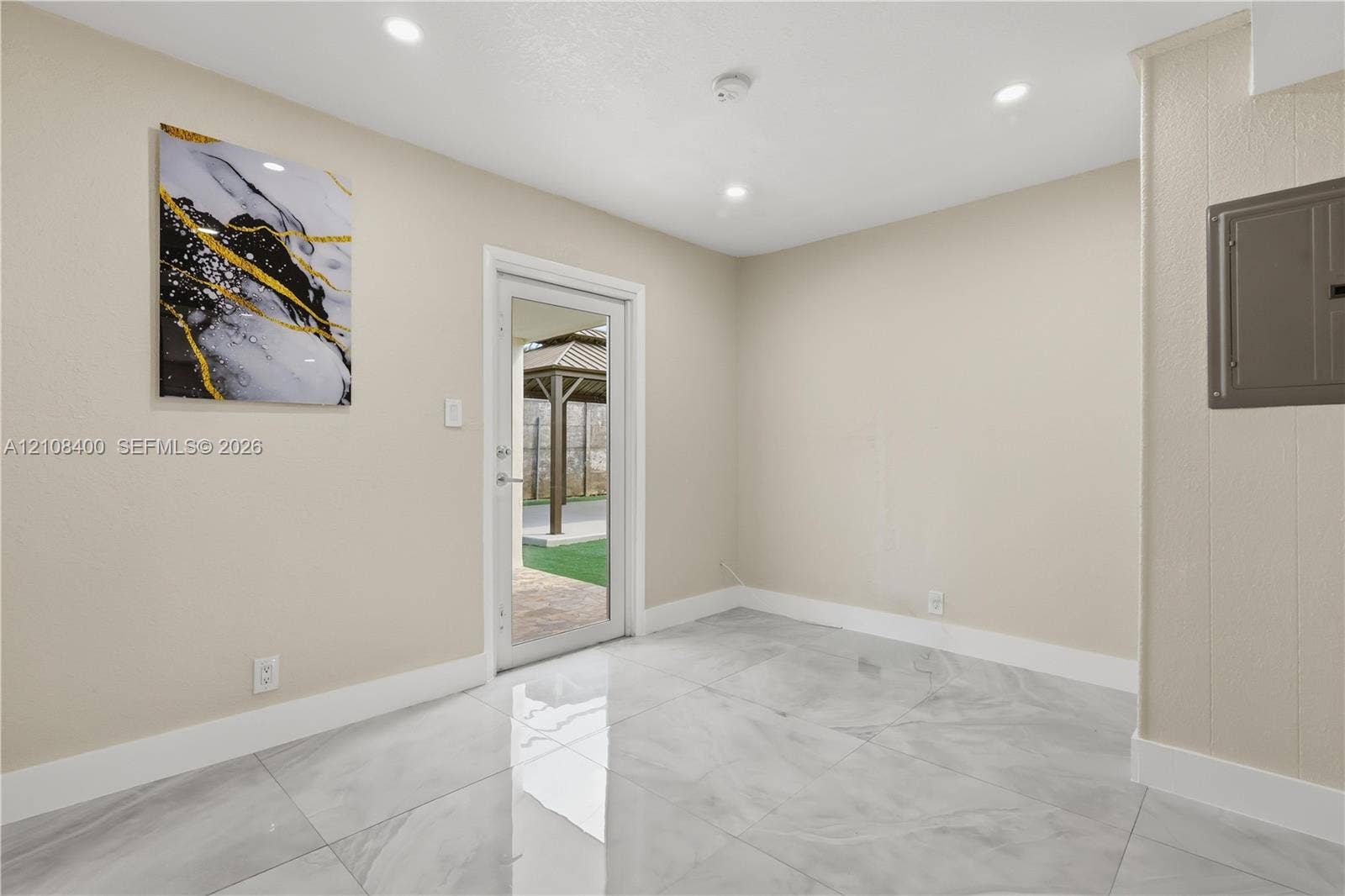 2551 SW 53rd Avenue, West Park, West Park, FL 33023 Neutral-toned interior space featuring large-format stone-finish tile flooring, recessed ceiling lighting, and a glass-paneled exterior door