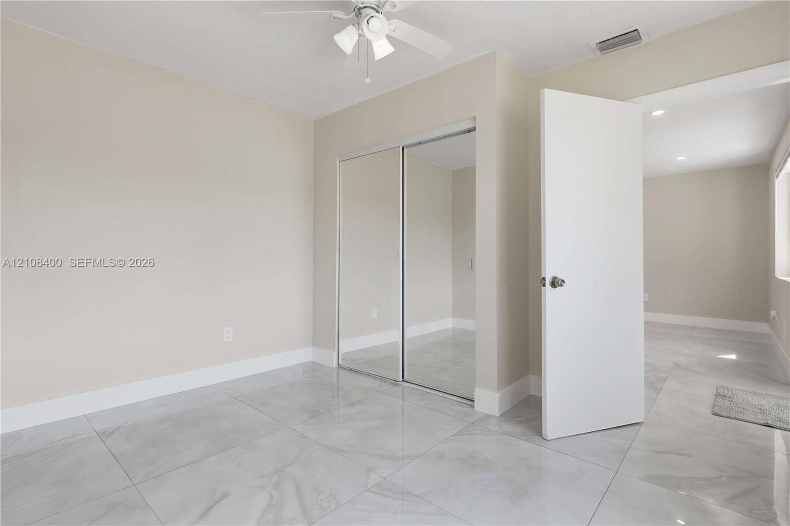 2551 SW 53rd Avenue, West Park, West Park, FL 33023 Room featuring large-format tile flooring, sliding mirrored closet doors, and a ceiling fan with integrated lighting