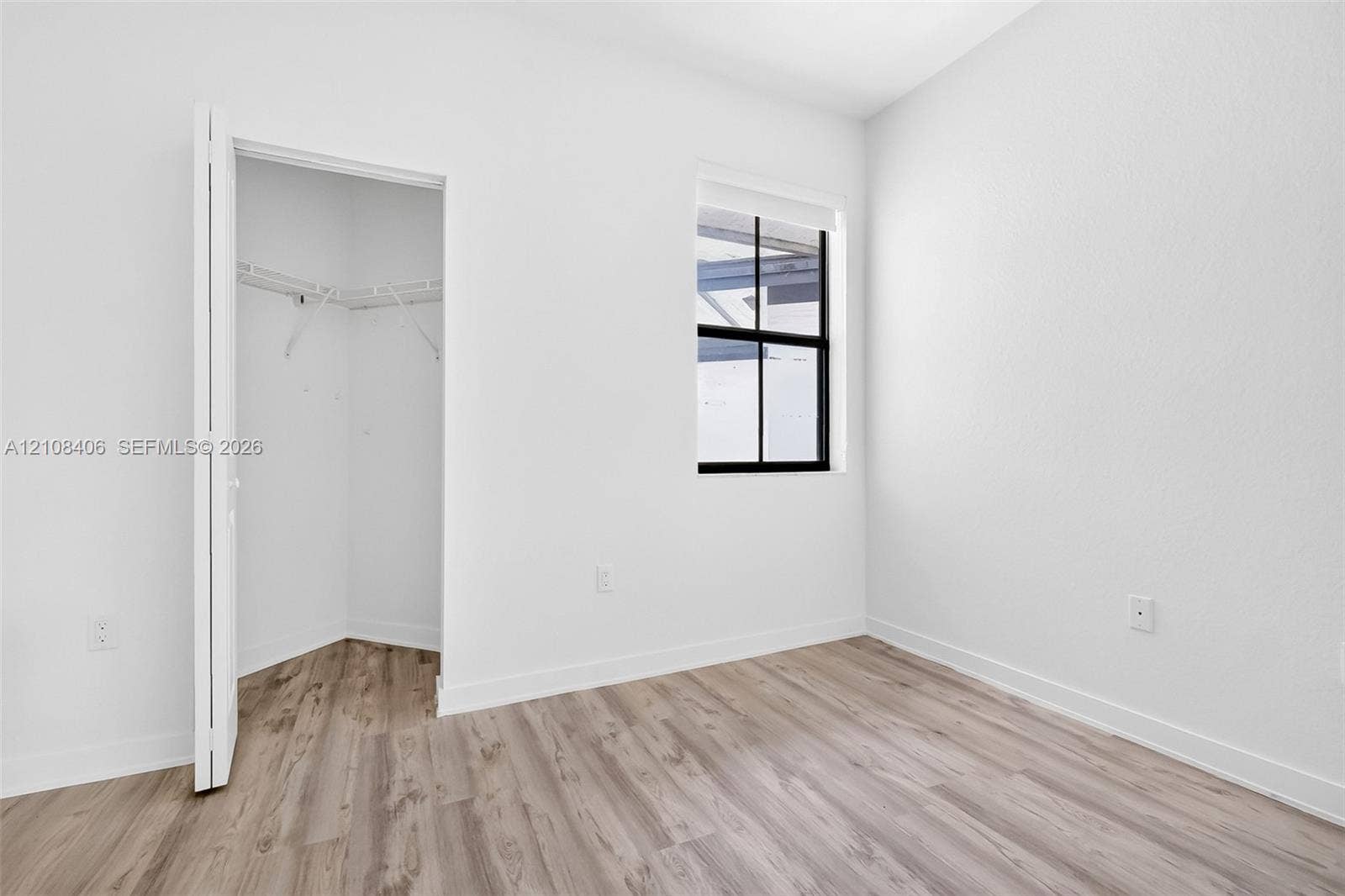 15650 SW 136th Street, #212, Miami, FL 33196 Neutral interior featuring wood-finish flooring, a black-framed window, and a walk-in closet with built-in wire shelving