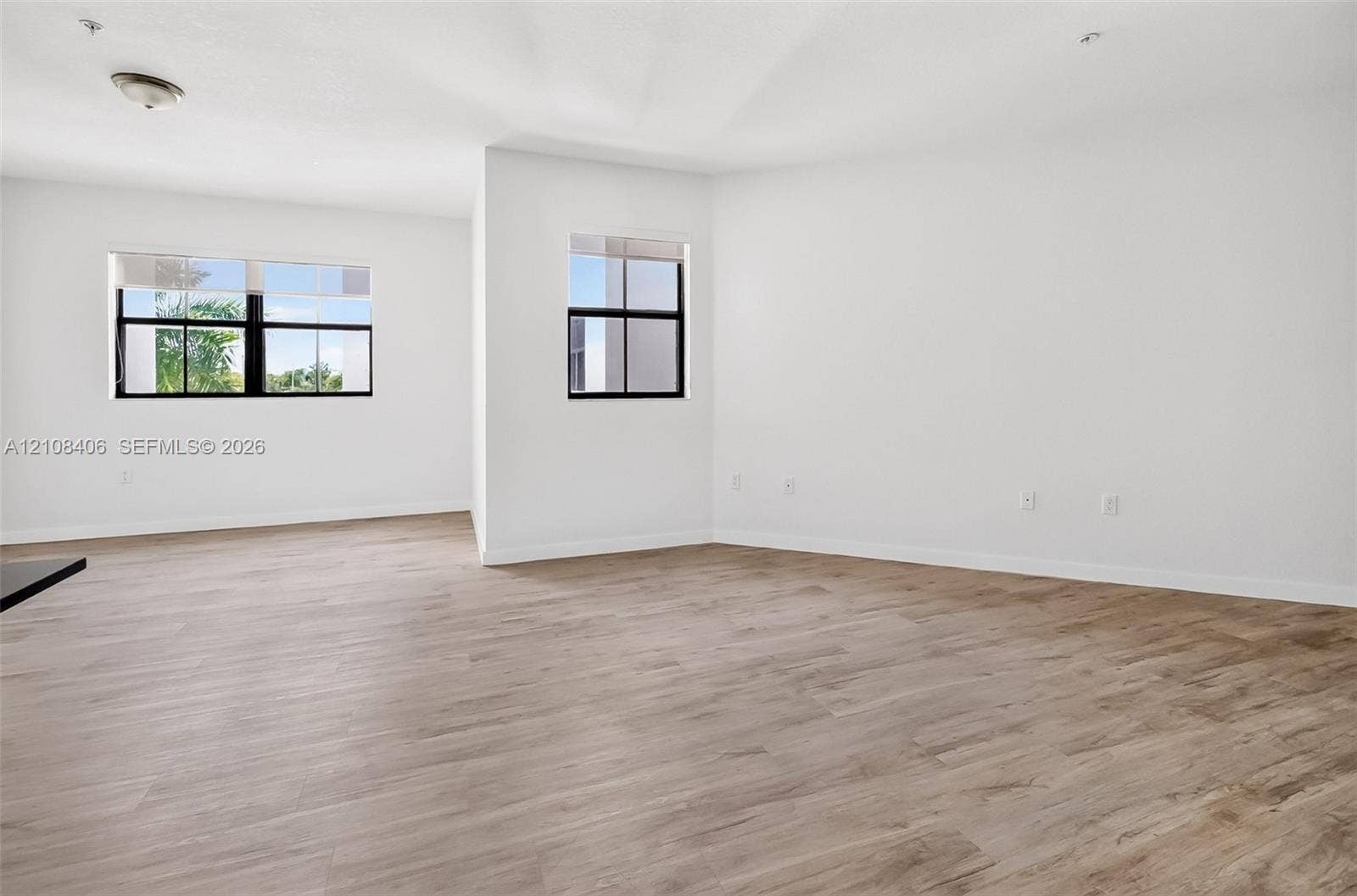 15650 SW 136th Street, #212, Miami, FL 33196 Neutral-toned wood-finish flooring, two large windows with black frames, and recessed lighting fixtures