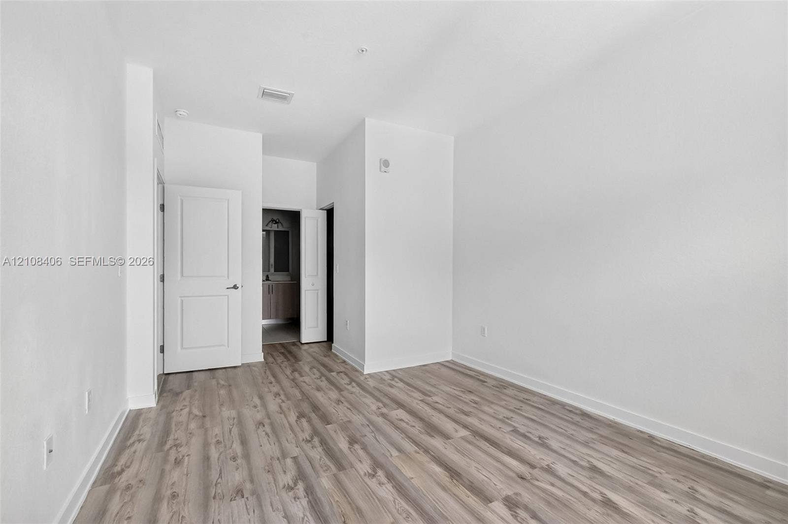 15650 SW 136th Street, #212, Miami, FL 33196 Neutral-toned wood-finish flooring, crisp white walls, and two-panel interior doors