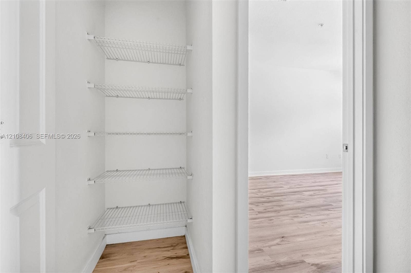15650 SW 136th Street, #212, Miami, FL 33196 Storage closet featuring five tiers of white wire shelving and wood-finish flooring