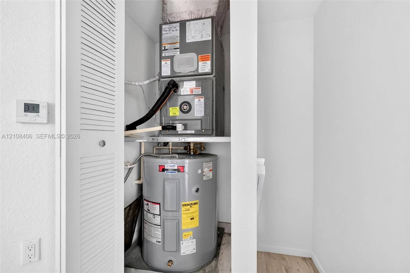 15650 SW 136th Street, #212, Miami, FL 33196 Utility closet featuring a stacked forced-air heating and cooling unit with an integrated water heater and louvered access door