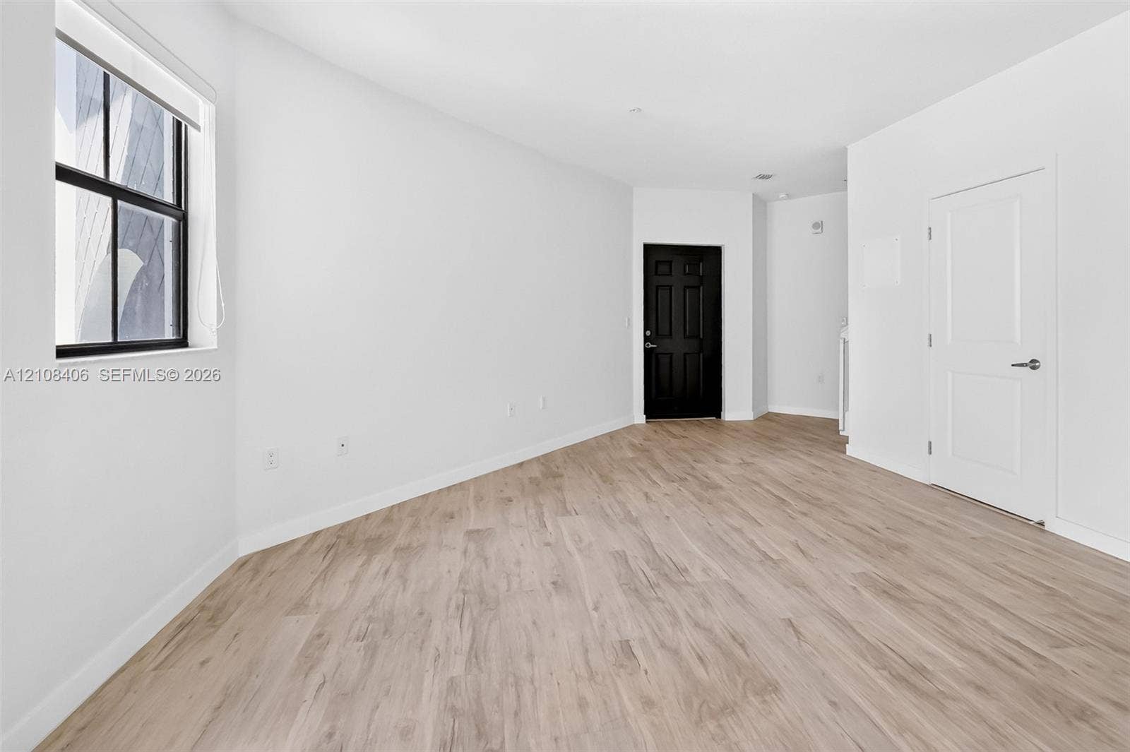 15650 SW 136th Street, #212, Miami, FL 33196 Neutral-toned wood-finish flooring, multi-pane window with black frame, solid-core black interior door, and white panel door