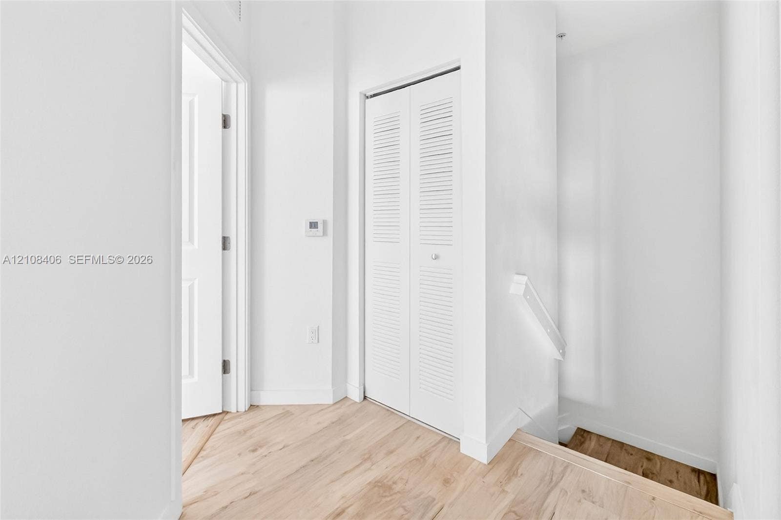 15650 SW 136th Street, #212, Miami, FL 33196 Neutral interior featuring wood-finish flooring, white paneled doors, and a louvered-style closet door