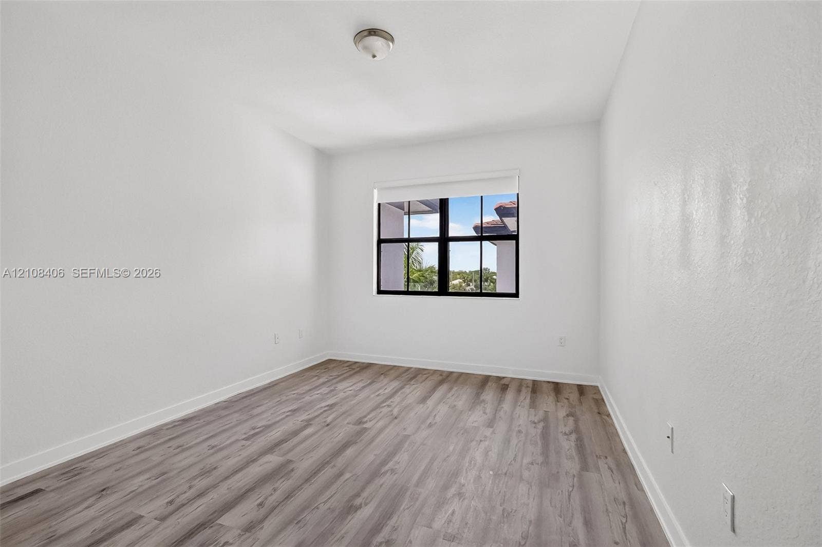 15650 SW 136th Street, #212, Miami, FL 33196 Interior space featuring wood-finish flooring, white walls, and a multi-pane window with black framing