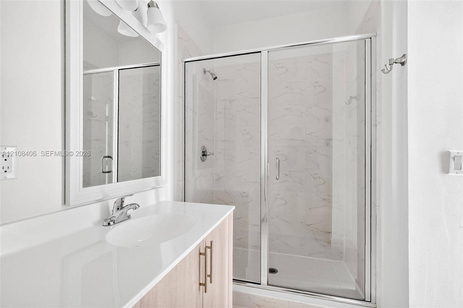 15650 SW 136th Street, #212, Miami, FL 33196 Bathroom featuring a light wood-finish vanity with a white countertop, walk-in shower with a glass enclosure, and wall-mounted mirror with integrated light fixtures