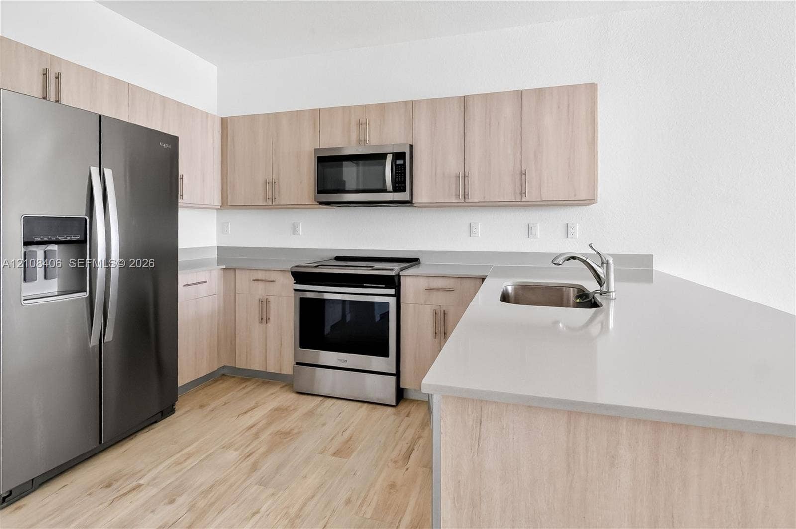 15650 SW 136th Street, #212, Miami, FL 33196 Kitchen featuring light-finish cabinetry, stainless steel appliances, quartz countertops, a dual-basin stainless steel sink, and wood-finish flooring