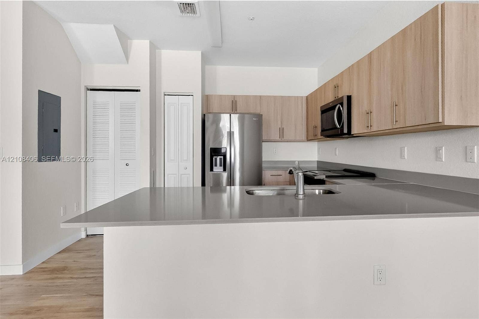 15650 SW 136th Street, #212, Miami, FL 33196 Kitchen featuring light-finish cabinetry, stone-surface countertops, stainless steel appliances, and wood-finish flooring