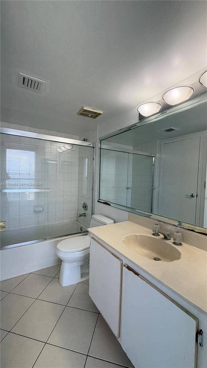 7601 E Treasure Drive, #618, North Bay Village, North Bay Village, FL 33141 Bathroom featuring a vanity with integrated sink, large wall-mounted mirror, sliding glass shower enclosure, tiled tub surround, and tile flooring