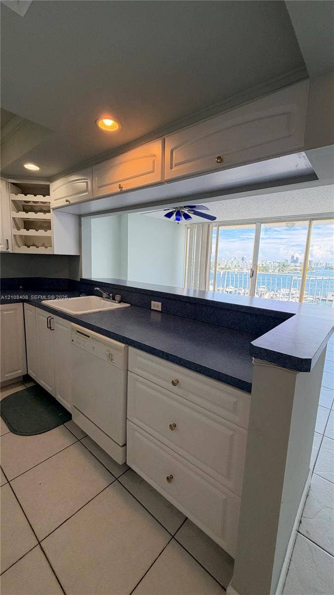 7601 E Treasure Drive, #618, North Bay Village, North Bay Village, FL 33141 Kitchen featuring white cabinetry with integrated wine storage, contrasting countertops, built-in dishwasher, recessed lighting, and tile flooring