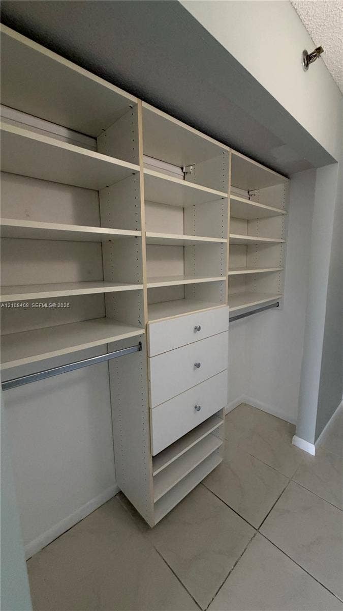 7601 E Treasure Drive, #618, North Bay Village, North Bay Village, FL 33141 Custom built-in closet organization system featuring adjustable white shelving, integrated drawers with hardware, and metal hanging rods