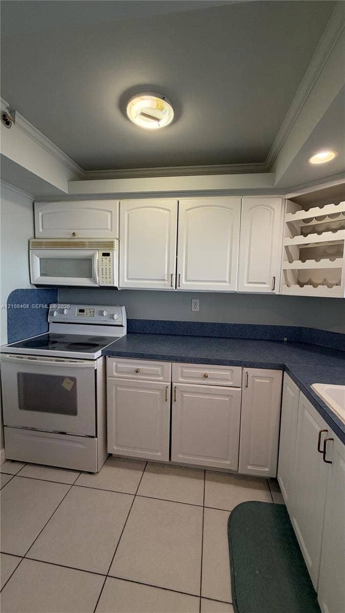 7601 E Treasure Drive, #618, North Bay Village, North Bay Village, FL 33141 Kitchen featuring white shaker-style cabinetry, a built-in wine rack, solid-surface countertops with an integrated backsplash, and tile flooring