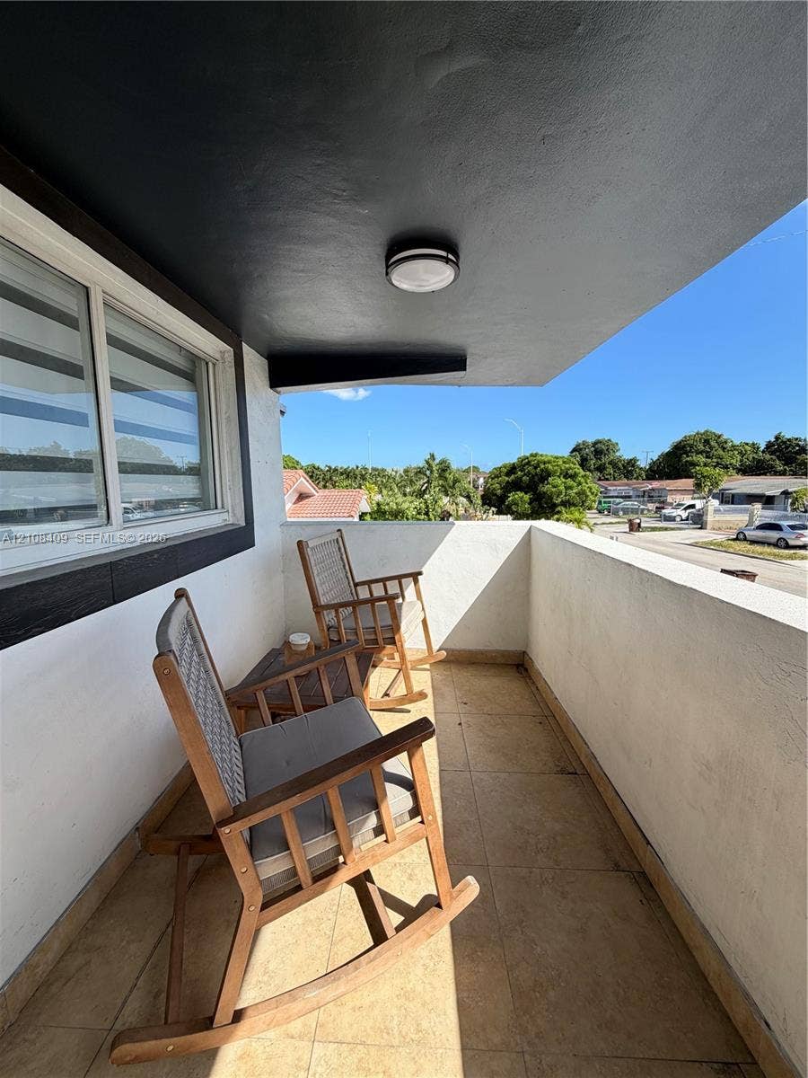 Covered balcony featuring tile flooring, smooth stucco walls, and a flush-mount ceiling light fixture