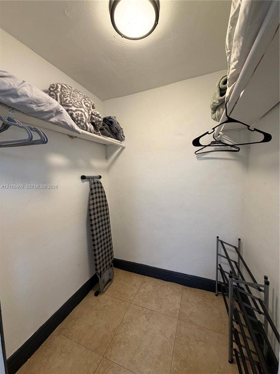 Storage area featuring tile flooring, ceiling-mounted lighting, and built-in shelving