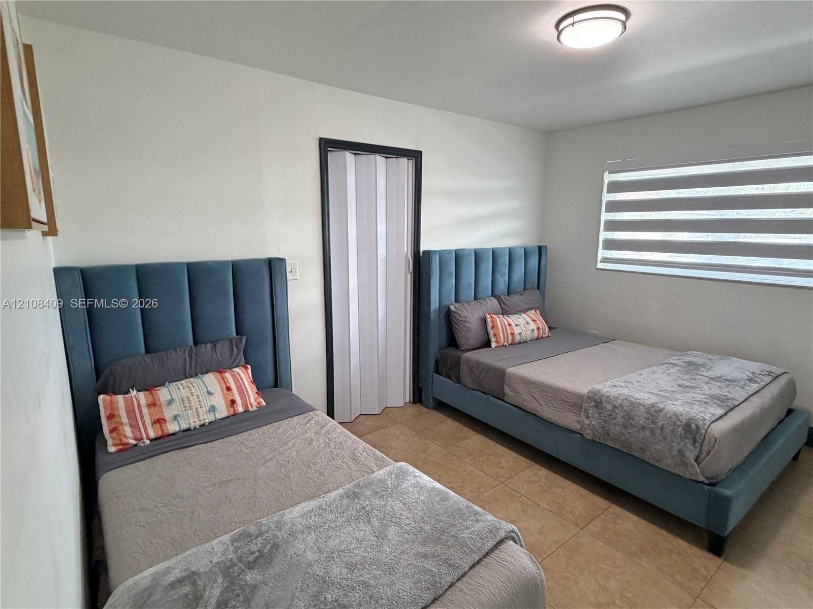 Room featuring neutral tile flooring, a minimalist ceiling-mounted light fixture, and a folding closet door