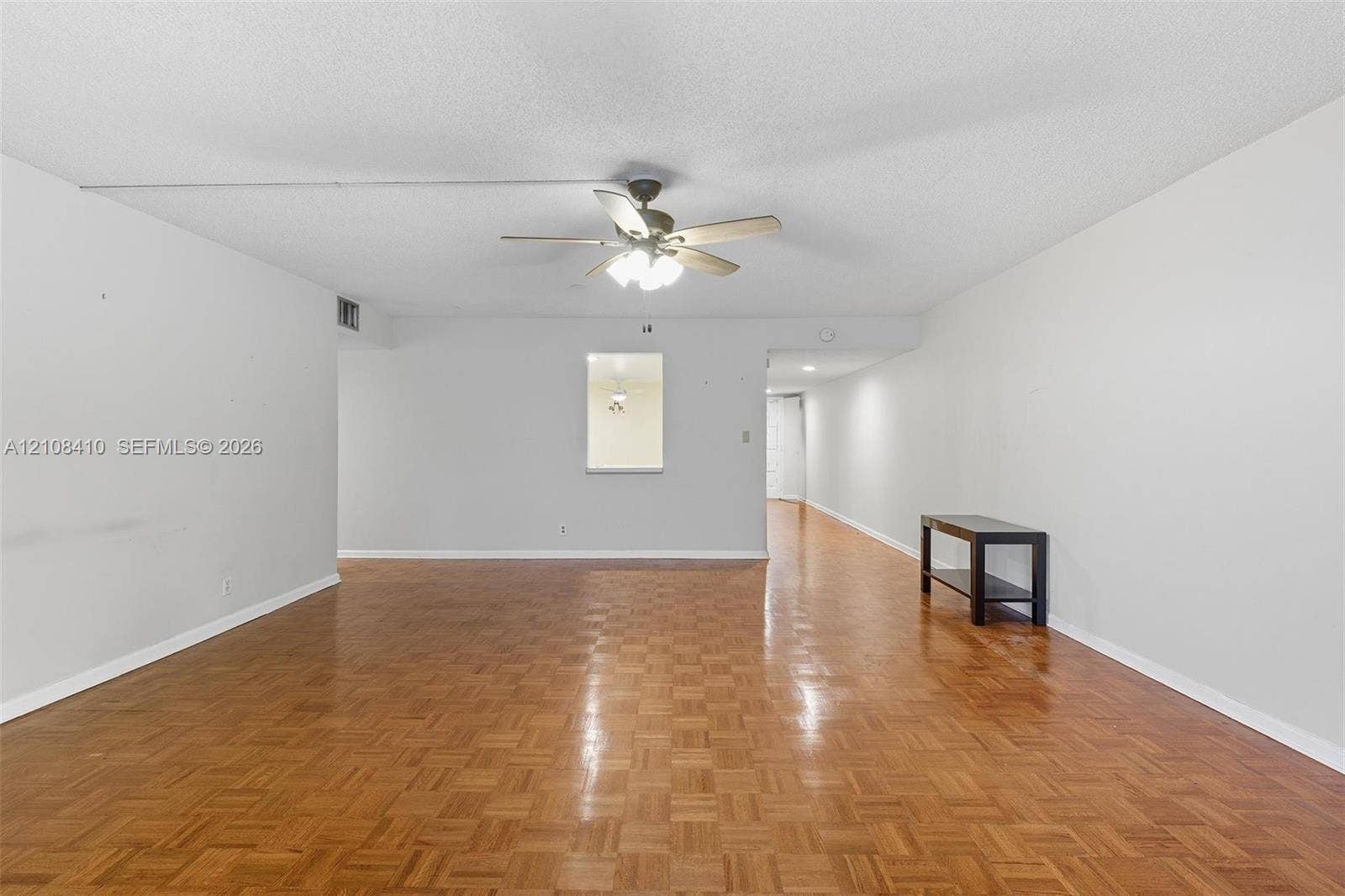 7556 Stirling Road, #124, Davie, Davie, FL 33024 Parquet wood-finish flooring, ceiling fan with integrated light fixture, and interior pass-through opening