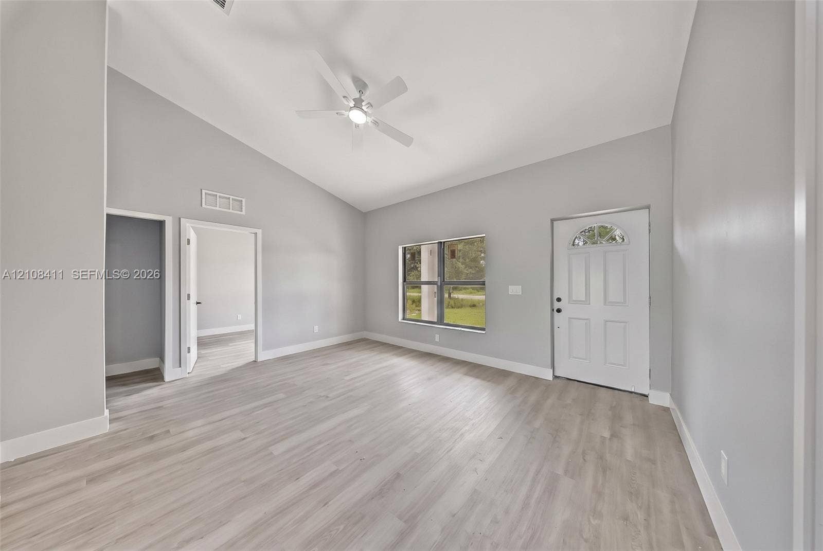 527 Avenida Del Sur, Clewiston, FL 33440 Interior space featuring vaulted ceilings, wood-finish flooring, a ceiling fan, and a six-panel exterior door with an arched glass insert