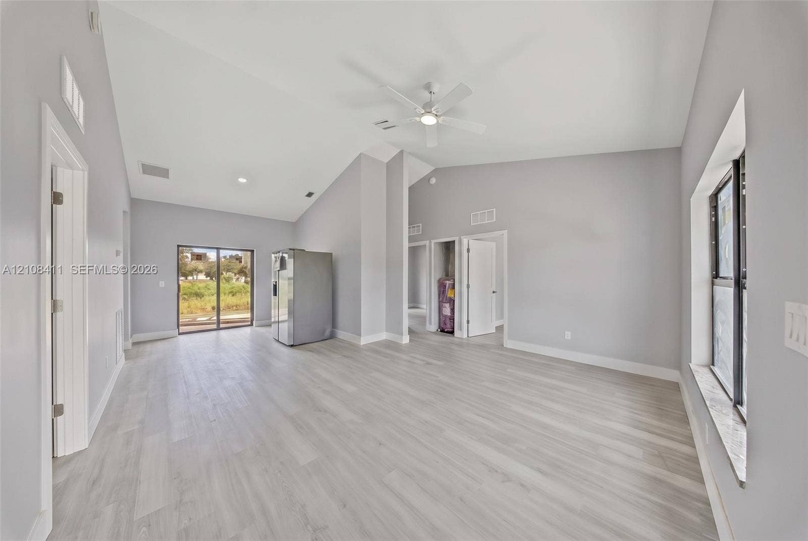 527 Avenida Del Sur, Clewiston, FL 33440 Open-concept interior featuring vaulted ceilings, wood-finish flooring, a ceiling fan, and sliding glass doors
