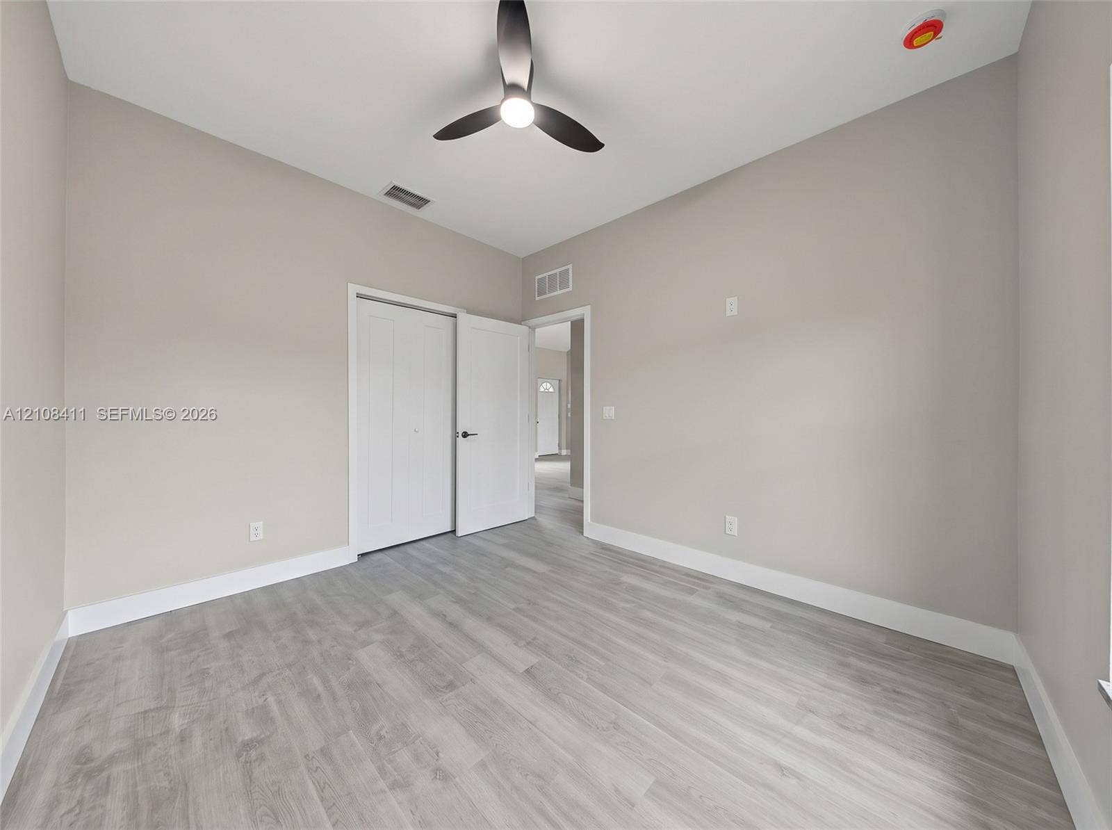 527 Avenida Del Sur, Clewiston, FL 33440 Neutral-toned interior featuring wood-finish flooring, a modern three-blade ceiling fan with integrated lighting, and a dual-panel closet door