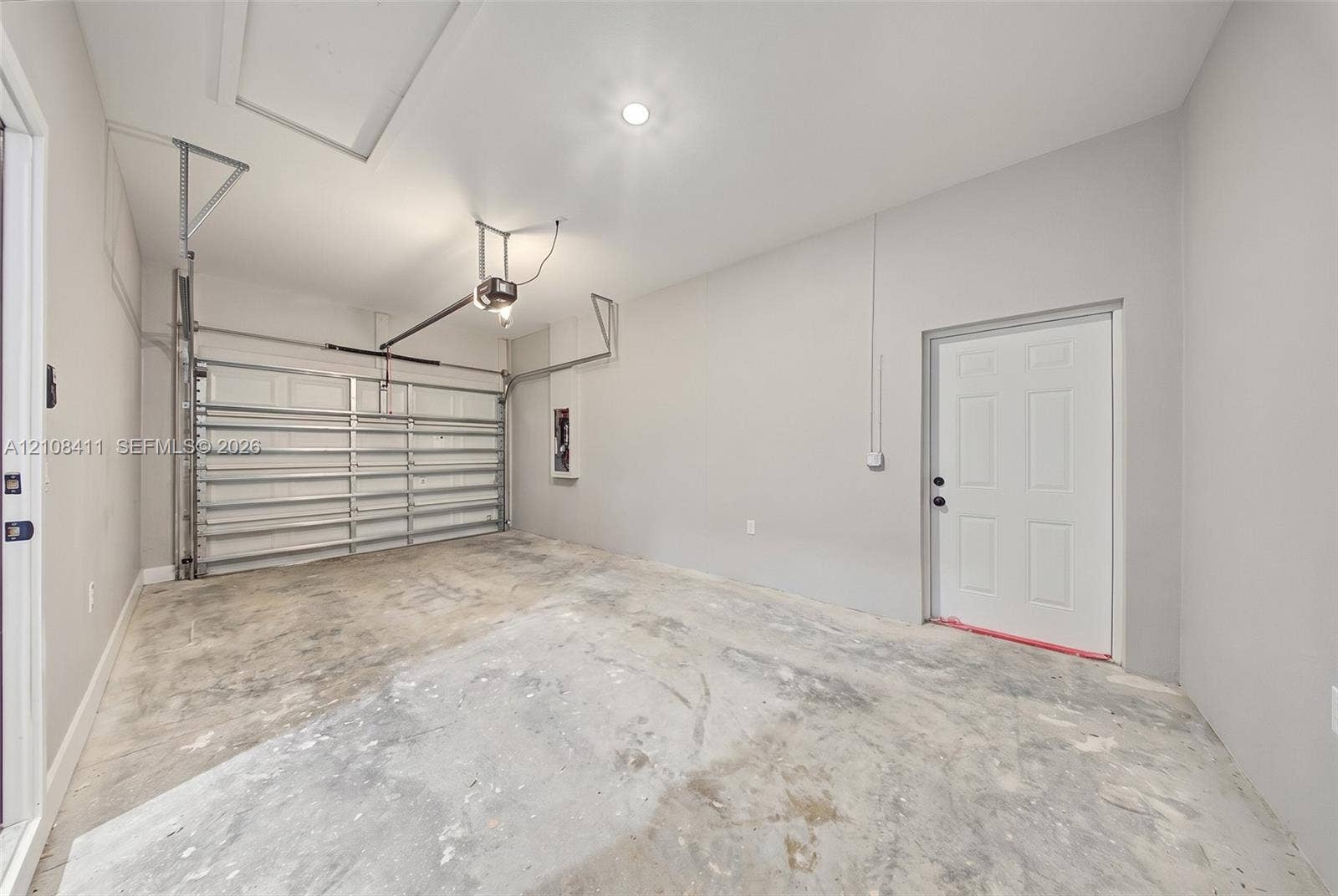 527 Avenida Del Sur, Clewiston, FL 33440 Finished garage featuring smooth-finish interior walls, a recessed ceiling light, an overhead garage door mechanism, and an exterior-access door