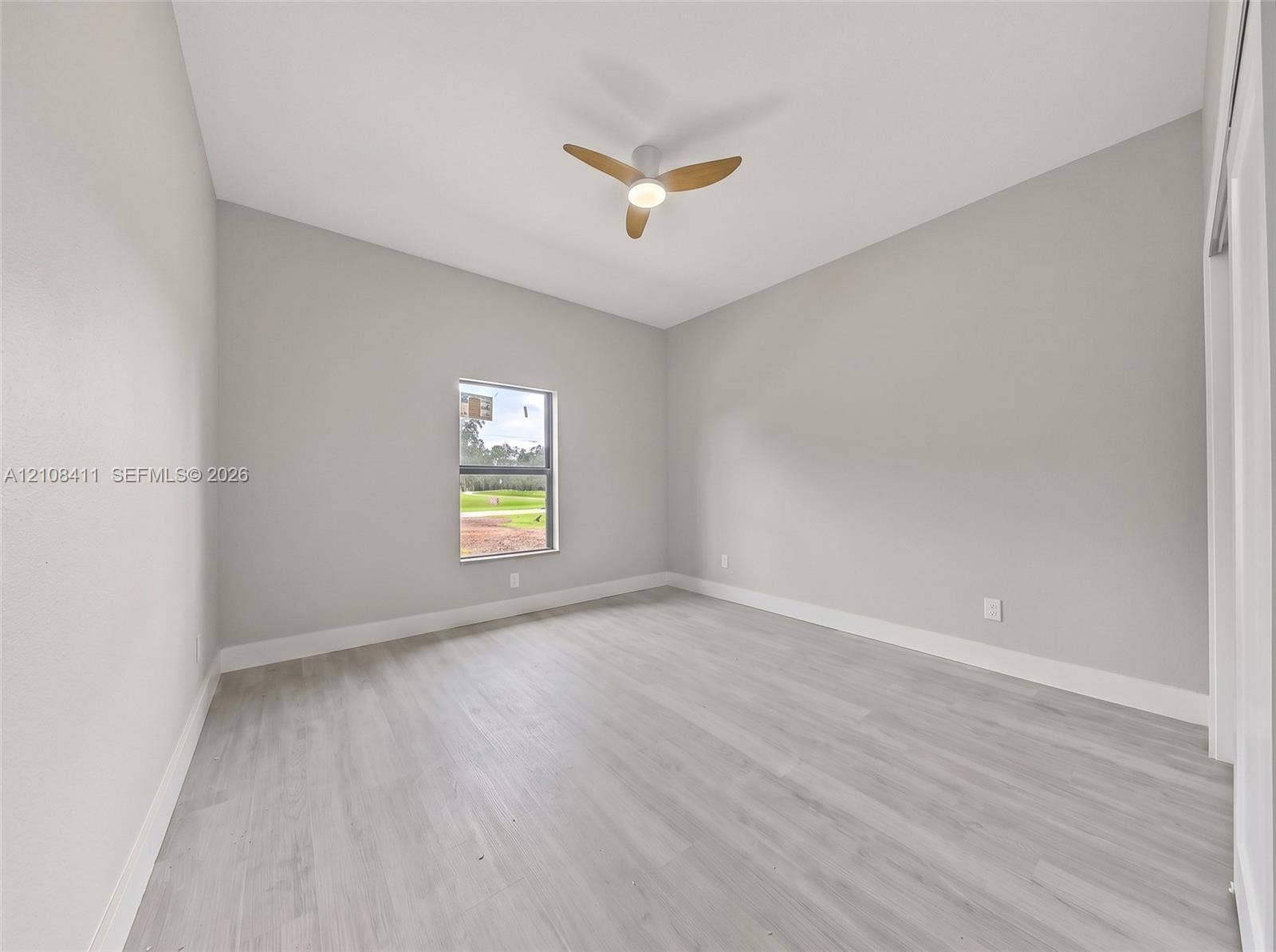 527 Avenida Del Sur, Clewiston, FL 33440 Neutral-toned interior space featuring wood-finish flooring, a contemporary three-blade ceiling fan with integrated lighting, and a single-pane window