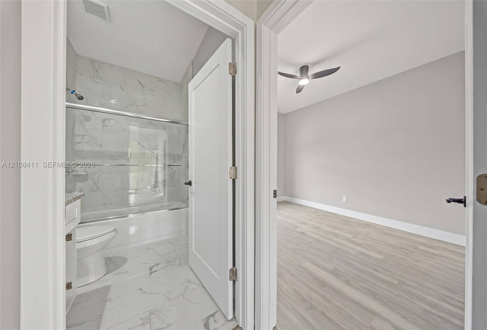 527 Avenida Del Sur, Clewiston, FL 33440 Full bathroom with a tub-shower combination featuring tile surround, and an interior room with wood-finish flooring and a ceiling fan