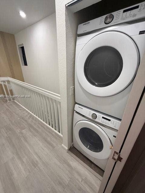 Stackable washer and dryer unit with white finish, wood-finish flooring, and white spindle railing